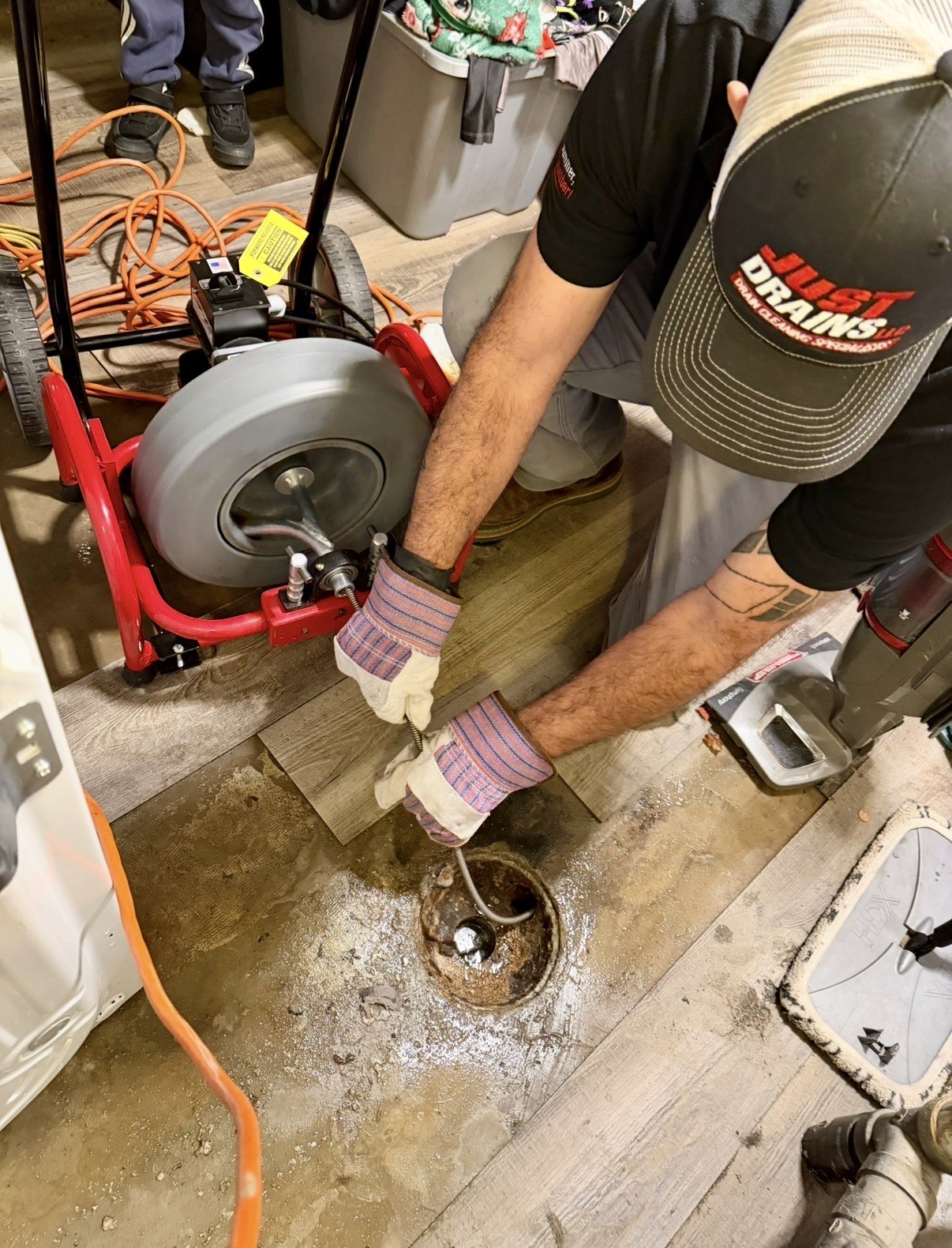 Just Drains technician using a cable machine to clear a drain